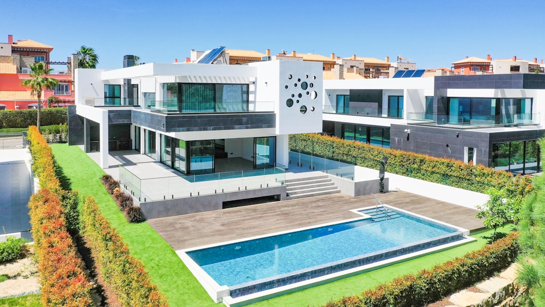 Modern white villa with a swimming pool, landscaped gardens, and solar panels under a clear blue sky
